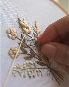 someone is stitching flowers on a white cloth