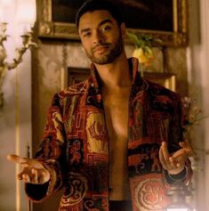 a shirtless man with his hands out in front of an ornate wallpapered room