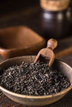 a wooden bowl filled with black tea on top of a table