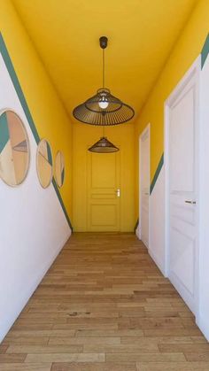 an empty hallway painted in yellow and green with three circular lights hanging from the ceiling