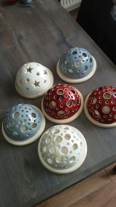 five ceramic bowls sitting on top of a wooden table with holes in them and stars painted on the lids