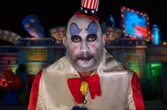 a creepy clown with an american flag hat on his head in front of a carnival