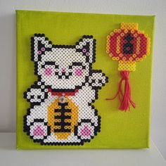 a cross - stitch picture with a cat and a flower on the wall next to it