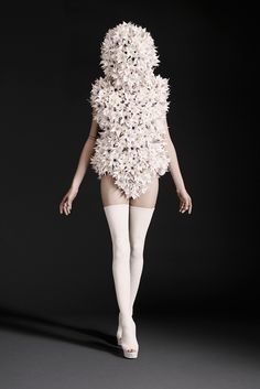 a woman is walking down the runway with flowers on her body