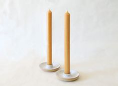 two candles are sitting on top of each other in front of a white background,