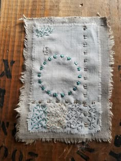 an old piece of cloth with stitching and beads on it sitting on top of a wooden table