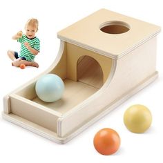 a child's wooden toy set with balls and a cat house on the floor