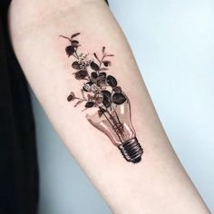 a light bulb tattoo on the arm with flowers in it and leaves growing out of it