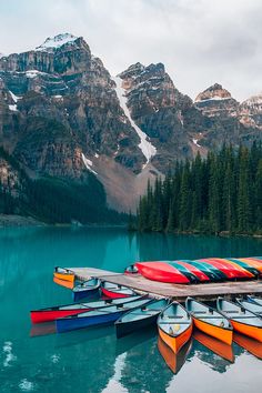 several canoes are docked at the edge of a mountain lake