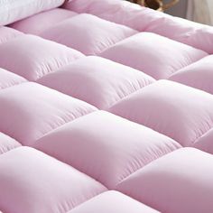 a close up of a pink mattress with white pillows on it and a brown dog in the background