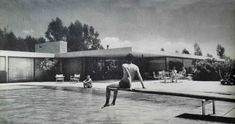 a man standing on the edge of a swimming pool in front of a large building