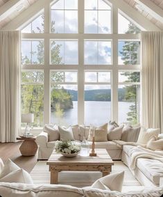 a living room filled with lots of furniture and large windows overlooking the water's edge