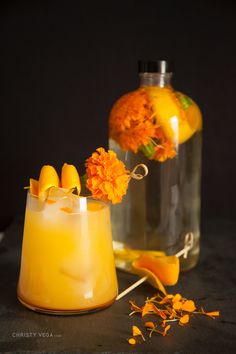 two glasses filled with drinks next to orange flowers