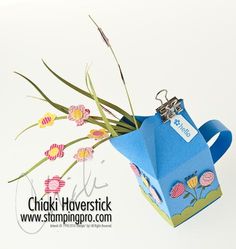 an origami watering can with flowers in it and a tag attached to the handle