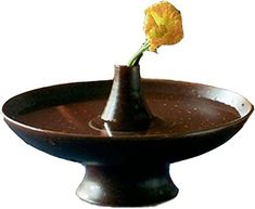 a single yellow flower in a brown vase