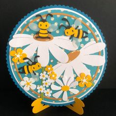 a paper plate with bees and daisies on the front, sitting on a black surface