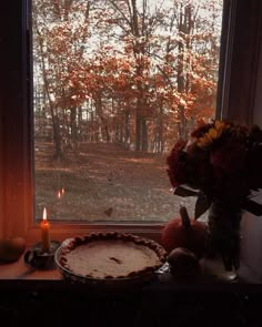 a pie sitting on top of a window sill next to a vase filled with flowers