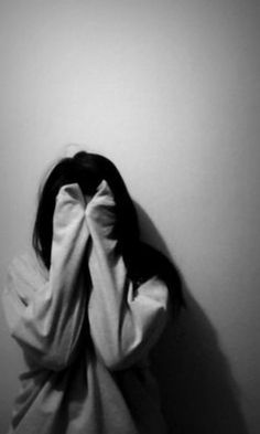 a woman covering her face with a blanket over her head, standing in front of a wall