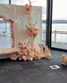 a wedding ceremony setup with candles and flowers on the floor next to a large window