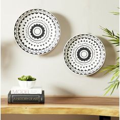 two black and white plates sitting on top of a wooden table next to a plant