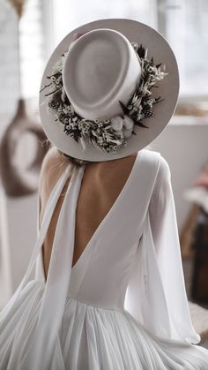 the back of a woman wearing a white hat with flowers on it's brim