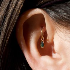 a woman's ear with a green stone in it