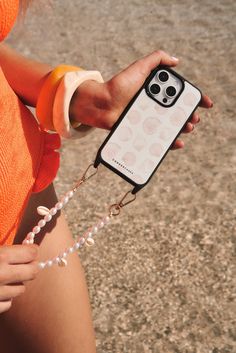 a woman is holding her cell phone in one hand and wearing an orange shirt on the other