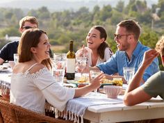 a group of people sitting around a table with food and drinks in front of them