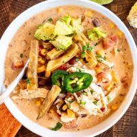 a white bowl filled with chicken tortilla soup and garnished with avocado