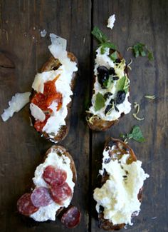 three pieces of bread with different toppings on them sitting on a wooden table top