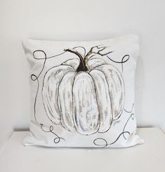 a white pillow with a black and white pumpkin design on the front, sitting on a table