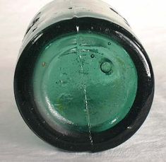 an old green glass vase sitting on top of a white table