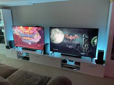 two large televisions sitting next to each other on top of a white entertainment center