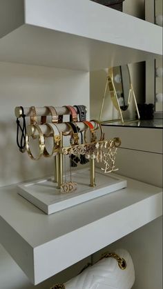 several pairs of bracelets and rings are on display in a white room with gold accents