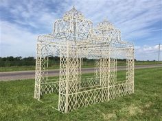 a white metal structure sitting on top of a lush green field next to a road