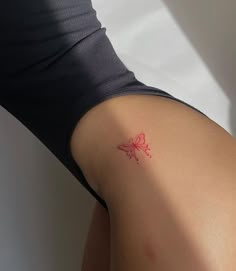 a woman's back with a red butterfly tattoo on her left arm and right leg