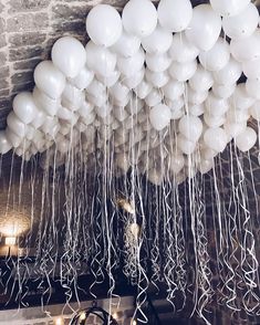 white balloons are suspended from the ceiling with streamers