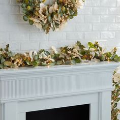 a white fireplace with a wreath on the mantle