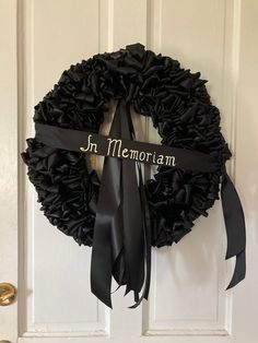 a black wreath with the words in memo written on it and a ribbon hanging from the front door