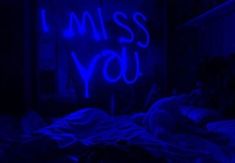 i miss you written on the wall next to a bed in a room with blue lights