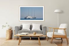 a living room filled with furniture and a large white sailboat floating in the ocean