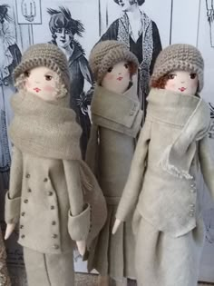 three dolls are dressed in coats and hats