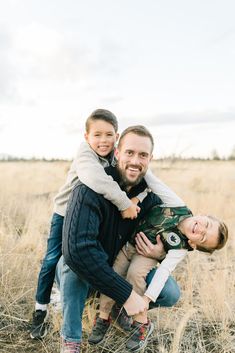 a father and his two sons are posing for a photo in the middle of a field