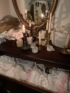 many candles are lit on a table in front of a mirror and some other items