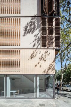 a building with wooden shutters on the side and people walking in front of it