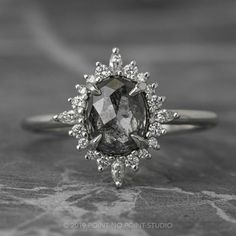 an engagement ring with a large gray diamond surrounded by small white diamonds on the side