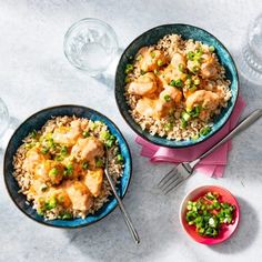 two bowls filled with chicken and rice next to some drinks on the side, along with silverware