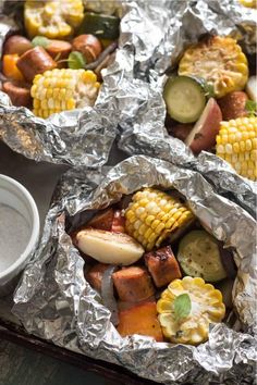 three foil wrapped trays filled with different types of food