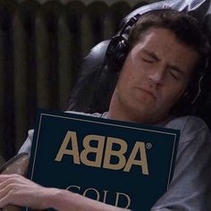 a man laying in bed holding a sign that says abra gold on the side