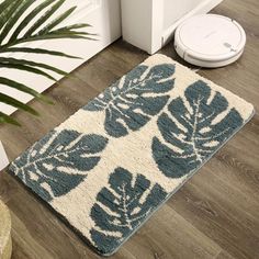 a blue and white rug with leaves on it next to a robot vacuum in the background